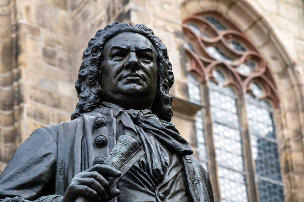 Close-up of the historical monument of the famous Baroque composer in the city center of Leipzig, created  in 1907 by Carl Seffner (1861-1932); in the background the St. Thomas Church