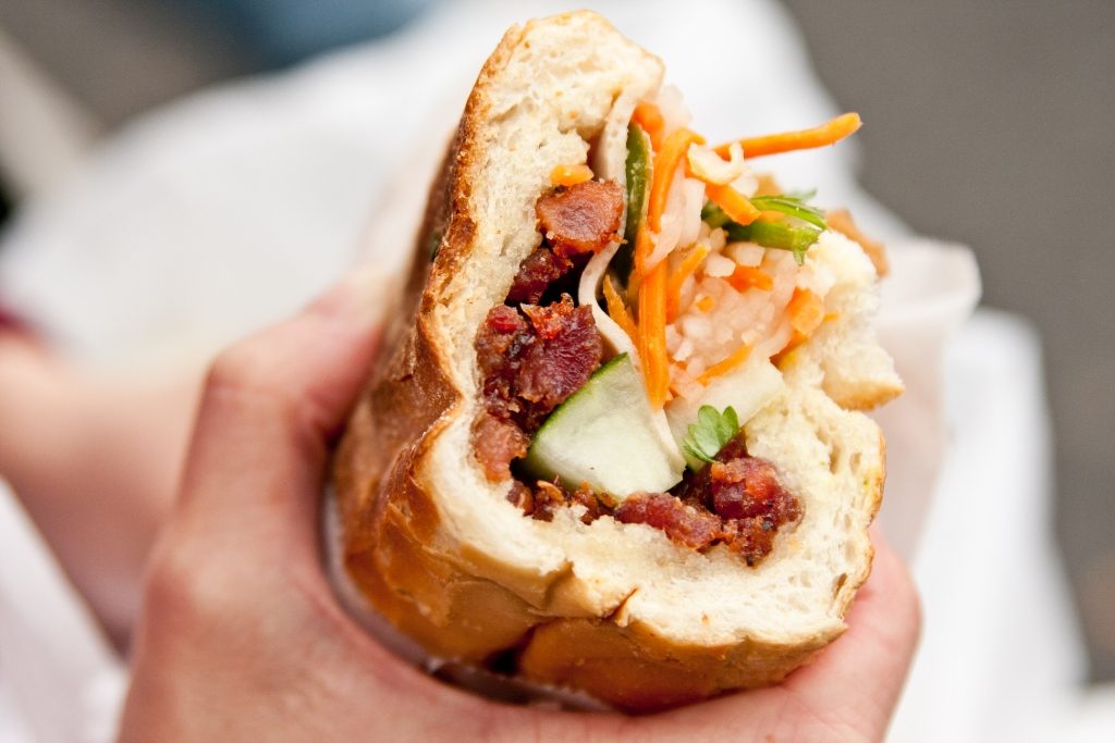 person holding a banh mi sandwich