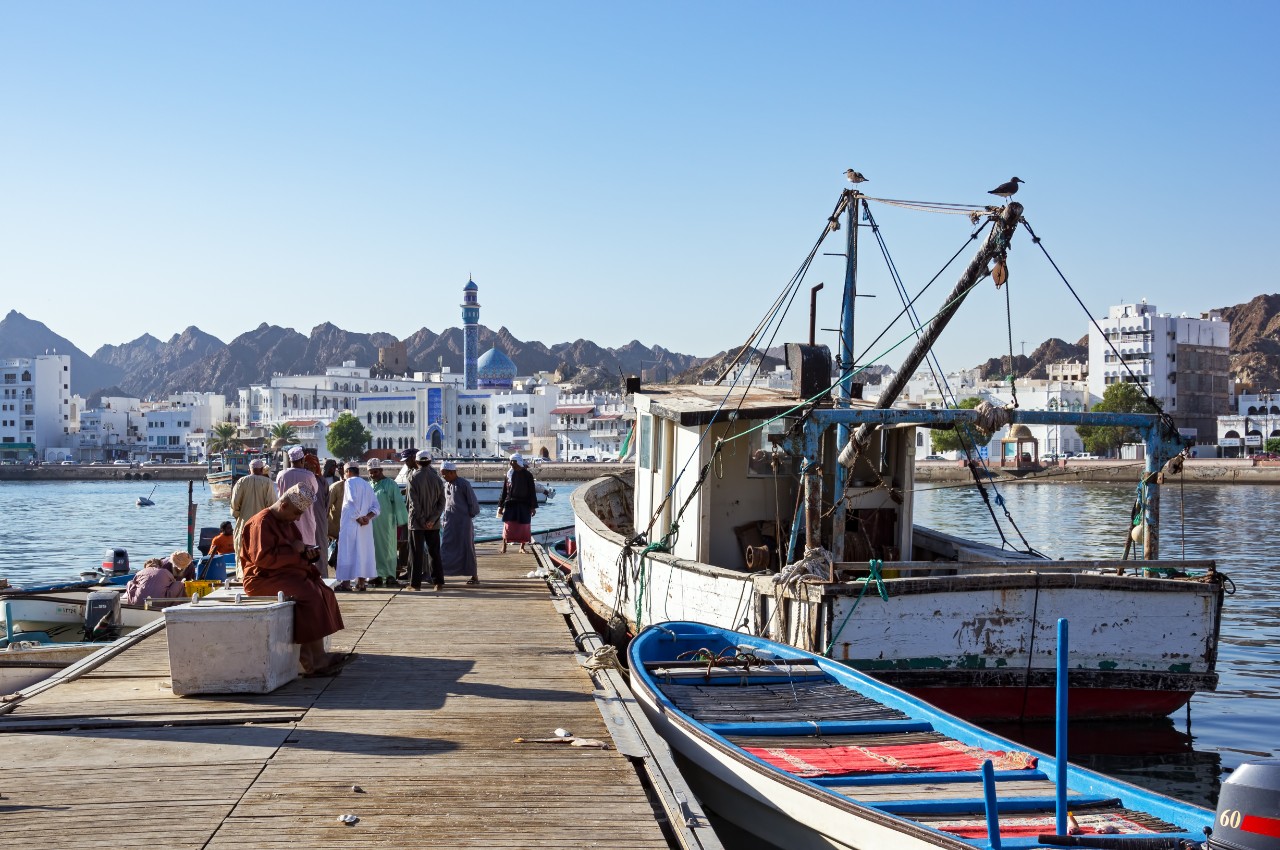 Fishermen at The Muttrah Fish docks with Muttrah corniche in the Background