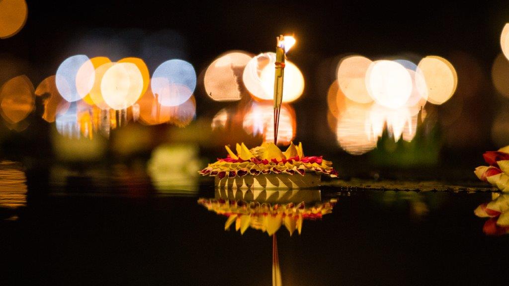 Floating lantern with flowers and incense at night.