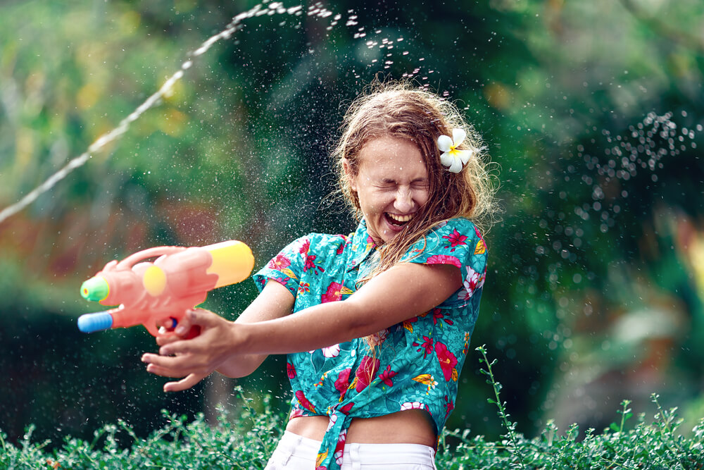 A colourfully dressed woman playing with a water gun