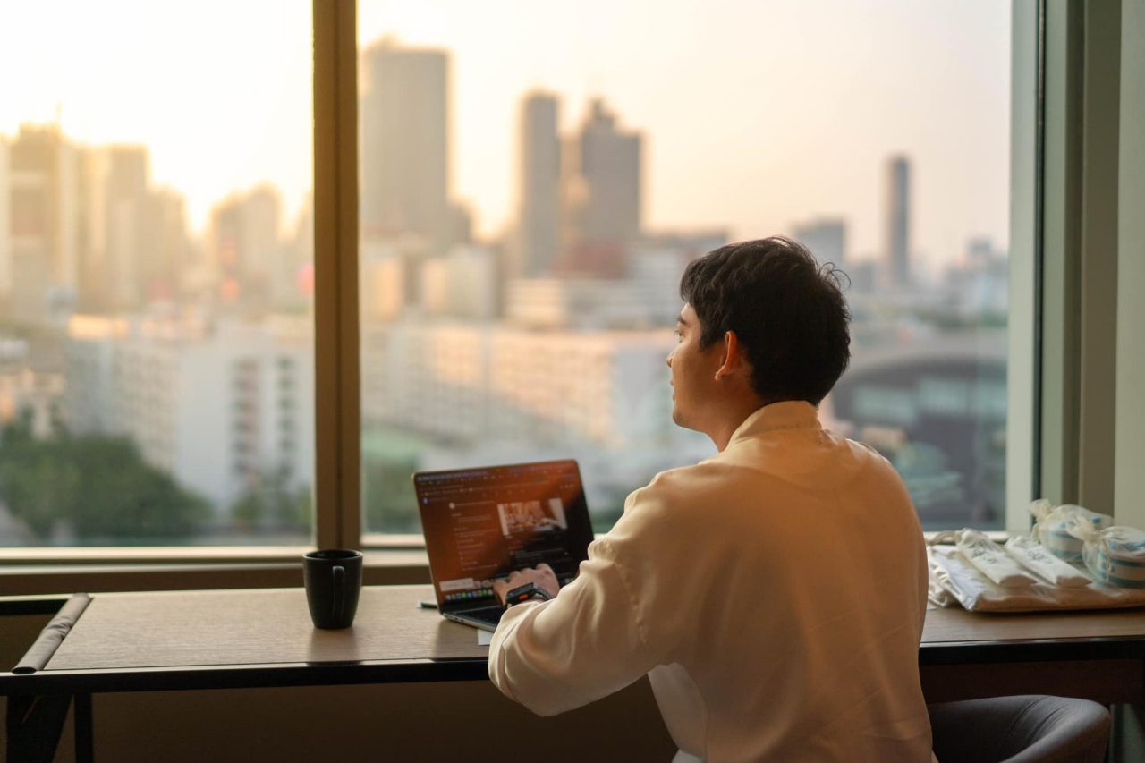  A man working on a laptop in front of a city view