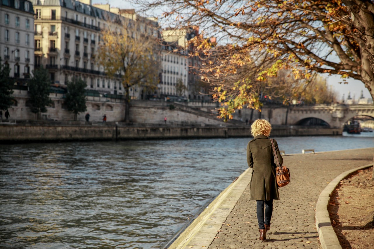 Rear View Of Young Woman Walking By Seine River